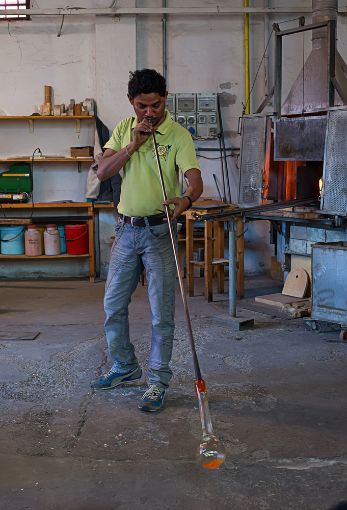 Soprador trabalhando uma peça de murano com a cana de assopro