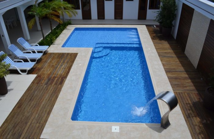 Piscina de fibra em L em residencia, com deck de madeira