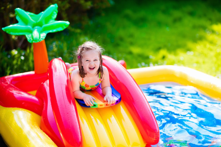 Criança brincando na piscina inflável no jardim.