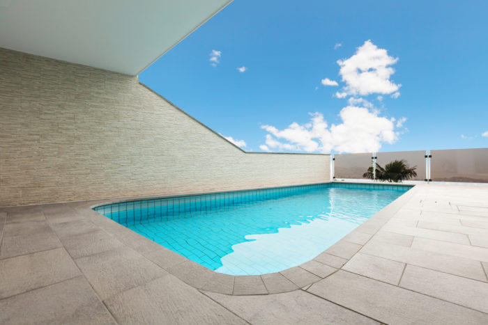 Piscina de concreto em varanda e piso de pedra.