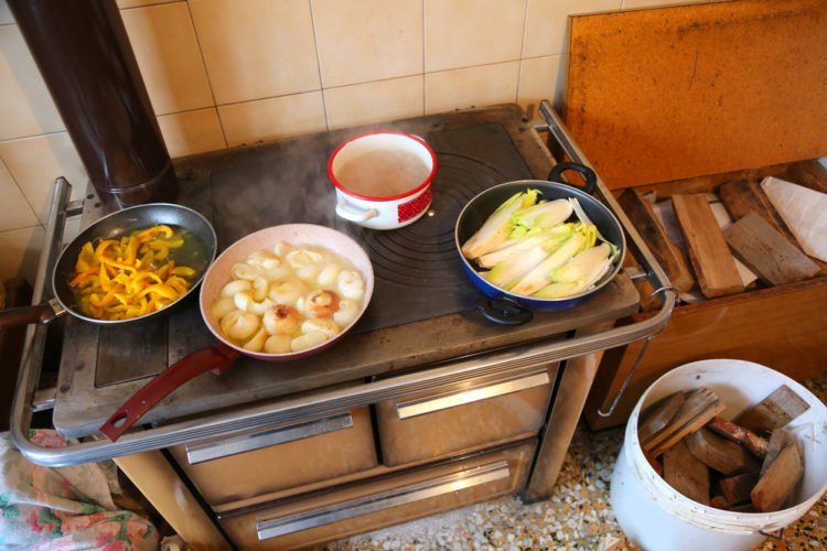 Panelas com comida sobre fogão a lenha de ferro